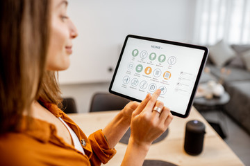 young woman controlling home with a digital touch screen panel. concept of a smart home and mobile a