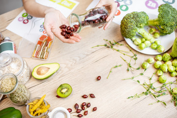 Holding dried rose hips at the table with healthy vegan food ingredients and supplements, top view. Concept of rose hips as a new trend in food and cosmetic industry