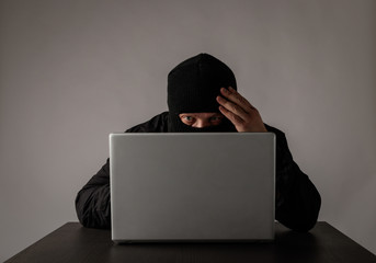 Hacker in mask using a laptop.