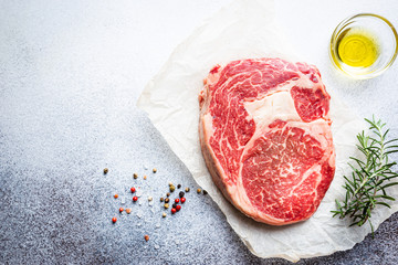 Wall Mural - Raw fresh meat Ribeye Steak and seasonings on light background, top view with copy space