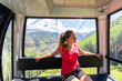 Young woman happy girl riding inside free cable car gondola by trees forest in San Juan mountains in Telluride, Colorado summer