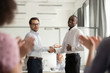 Millennial boss handshake black colleague congratulating with promotion