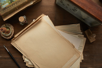 top view of vintage paper, painting, fountain pen, stamp and clock on wooden table