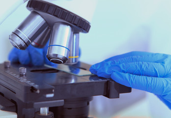 Poster - Close up of woman hand laying samples on glass under microscope lens