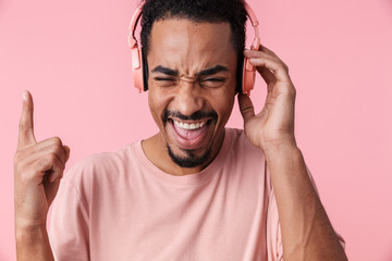 Wall Mural - Photo of delighted african american man using headphones