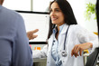 © H_Ko - Beautiful cheerful female GP communicating with male visitor