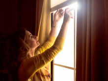 Home Blinds Window Shades Woman Opening Shade Blind During Sunny Morning. Mature Woman Holding Modern Cordless Top Down Luxury Curtains Indoors.