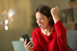 © Antonioguillem - Excited woman in red checking phone news in the night