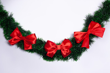 On tinsel green, hanging three red bows. White background.