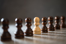 Authenticity and uniqueness concept. White pawn standing in a line, selective focus.