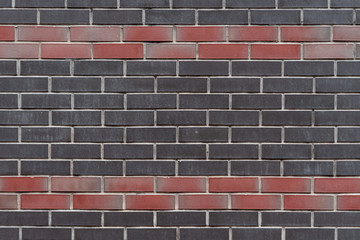 Wall texture of modern black and red rough brick. Grunge design of surface background. Vintage brickwall. Motley brickwork.