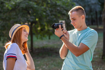 Wall Mural - Young teenage couple taking pictures of one another outdoors in sunny summer park.