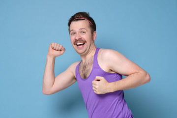 Running mature caucasian man in colored t-shirt on blue wall