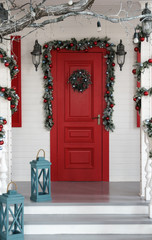 Decorated red door for Christmas holidays with blue lanterns on the stairs