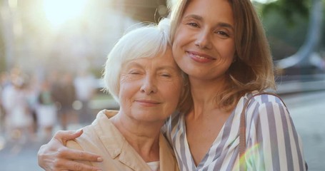 portrait shot of the caucasian pretty happy woman hugging her senior mother and they smiling while l