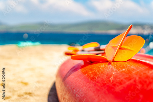 Fotomural Kayak with paddles lying on the sea shore