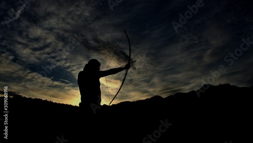 Fotomural Die Silhouette eines Bogenschützen bei Sonnenuntergang