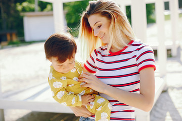 Pretty mother with little daughter. Family in a park. Little girl in a yellow clothes