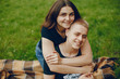 © hetmanstock2 - Lovely couple in a summer park. Boy with his girlfriend. Girl with guy sitting on a grass