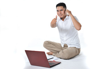 Portrait of Asian businessman sitting at white floor and calling on the phone pointed at the camera