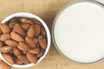 Wall Mural - Almond milk in bowl and almonds nuts on sack background /