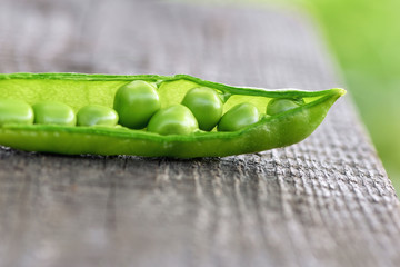 Peas. Close-up of one green open pod lying on a wooden Board in the garden. Macro horizontal photography