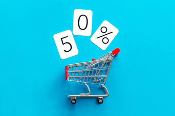 50% off discount - sale concept with shopping trolley cart - on blue background top-down copy space