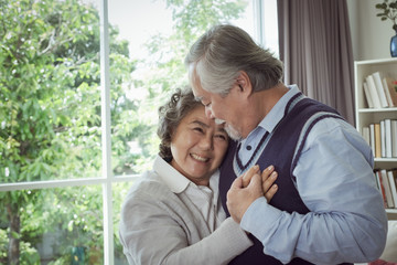 Wall Mural - Happy couple old elderly senior man hug woman and put hand on heart and happy with smiling together at home, retirement and healthcare lifestyle and lover relationship concept