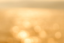 Delicate Golden Texture Bokeh Background. Blurry Yellow Bokeh Glare On The Water During Sunset And Dawn