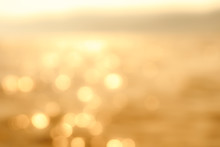 Delicate Golden Texture Bokeh Background. Blurry Yellow Bokeh Glare On The Water During Sunset And Dawn