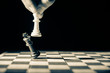 © GlobalReporter - Close up of white king taking down black king. Hand and fingers and chess board with vintage look