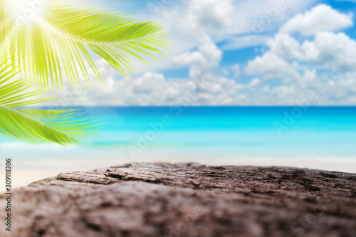 Blur tropical beach with bokeh sun light wave and palm tree on empty old wood...