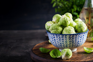 Fresh organic brussels sprouts in a bowl on a dark background. Healthy food. Vegan/vegetarian meal.