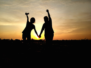 silhouette of childhood moment. happy young girl holding hand enjoying sunset in field. children day