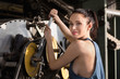 Beautiful girl repairs the spinning machine with an adjustable wrench