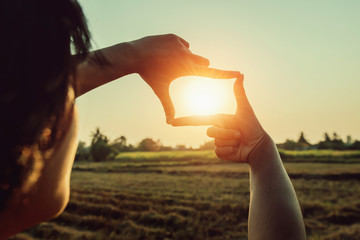 woman hand framing view distant over sunset. business concept