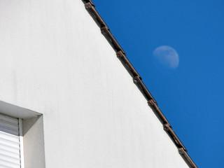 Roof tiles edges with shutter closed and moon in the back