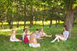 © Andrey - children hold a lesson with the teacher in the park on a green lawn.