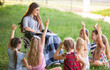 © Andrey - children hold a lesson with the teacher in the park on a green lawn.