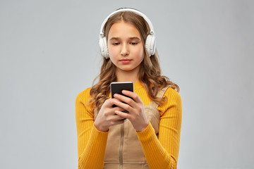 Poster - audio equipment and technology people concept - teenage girl in headphones listening to music on smartphone over grey background