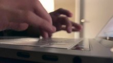 Someone busy typing on a keyboard of a aluminium Apple MacBook Pro laptop with touchbar and retina display, during the night with a bright lamp on in the background