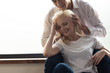 © LIGHTFIELD STUDIOS - Smiling man touching hair of girlfriend while sitting on windowsill