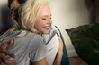 © LIGHTFIELD STUDIOS - Smiling blonde girl with closed eyes hugging boyfriend at home