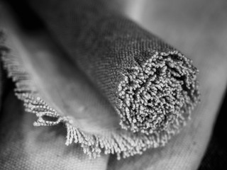 black and white photo of frayed tatty rolled up textile rug, coarse fabric