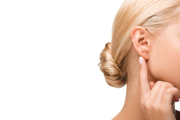 cropped view of blonde girl pointing with finger at ear isolated on white
