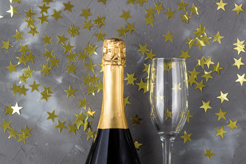 Champagne bottle and glasses with gold confetti stars. Concept for christmas, birthday or wedding