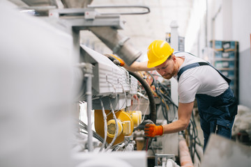 Factory worker. Man with helmet working on wires.	