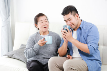 Wall Mural - Asian senior grand mother and son drinking coffee and talking happy and smile face in living room