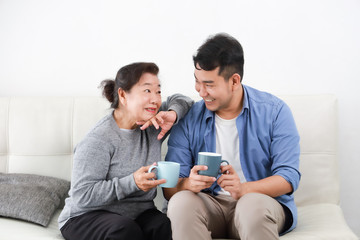 Wall Mural - Asian senior grand mother and son drinking coffee and talking happy and smile face in living room