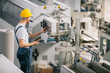 © JustLife - Man with helmet working in factory.